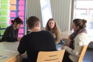 Studierende bereiten am Tisch und an der Pinwand ein Rollenspiel vor